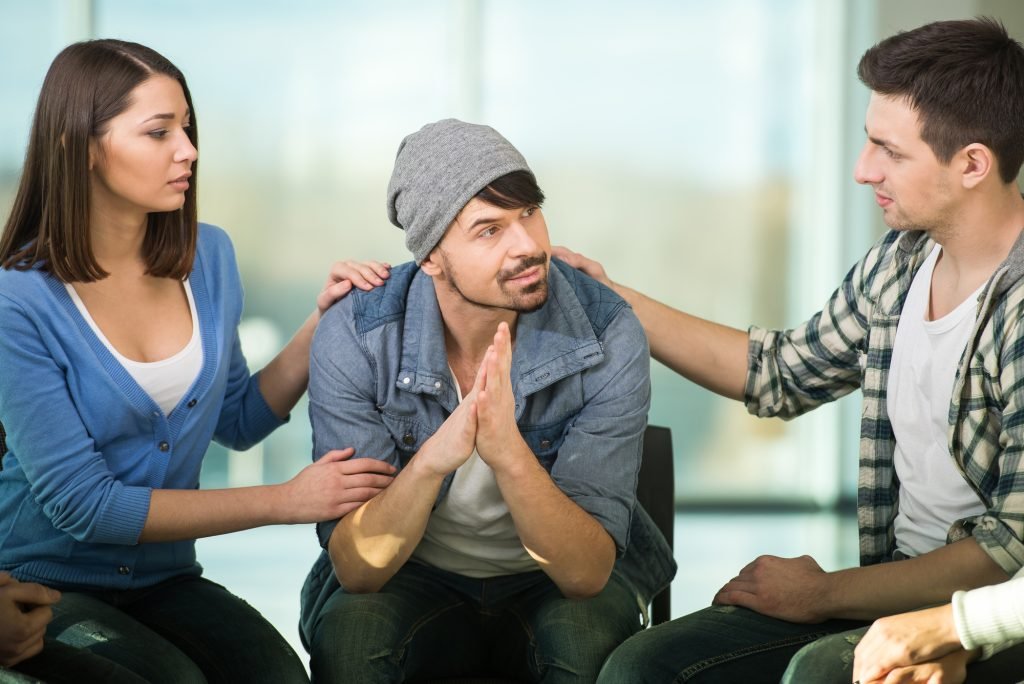 Members of a support group listening to a recently divorced man share his personal experience after divorce.